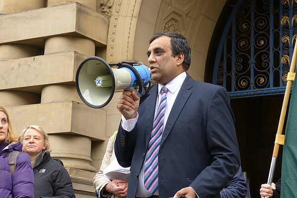 Shaffaq Mohammed speaking into a megaphone in front of Sheffield Town Hall