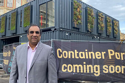 Cllr Shaffaq Mohammed next to the containers