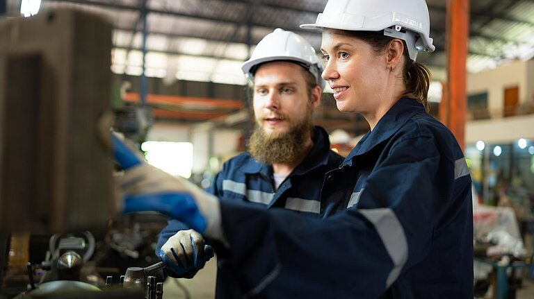 Two people using a machine.