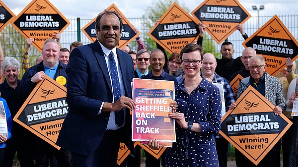 Shaffaq Mohammed and Hannah Kitching in front of a team of Sheffield Liberal Democrats holding orange diamonds
