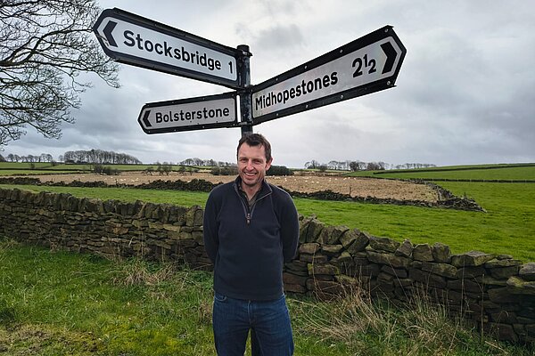 Stuart stood in front of a sign for Stocksbridge, Bolsterstone, and Midhopestones