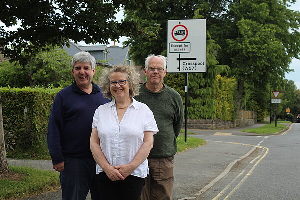 Cliff (right) Sue (middle) Andy (left) in front of a road safety sign they secured